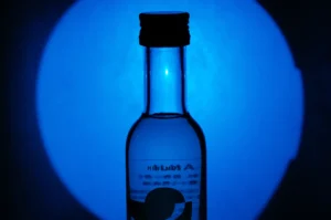 A silhouetted bottle against a blue circular background.