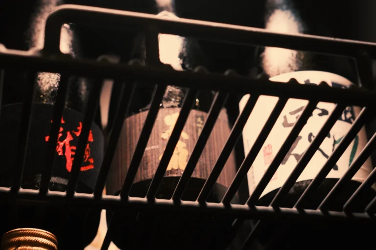 Bottles of sake in a refrigerator, partially obscured by a metal rack.