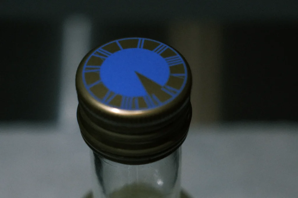 Close-up of a bottle cap with a blue clock design and a gold rim.