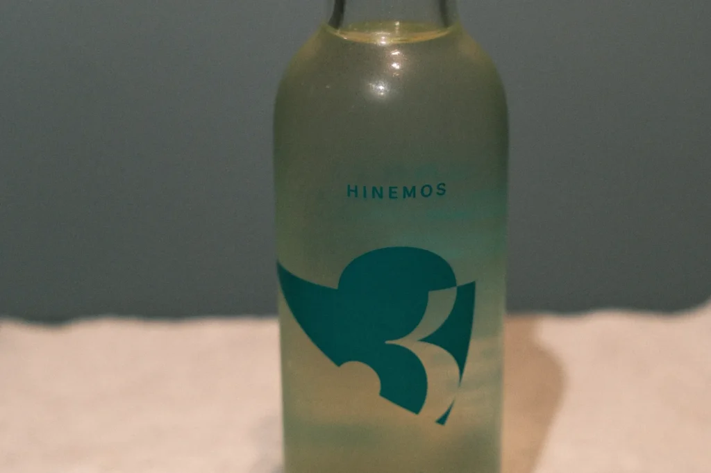 A bottle of Hinemos sake with a distinctive teal logo on a light background.