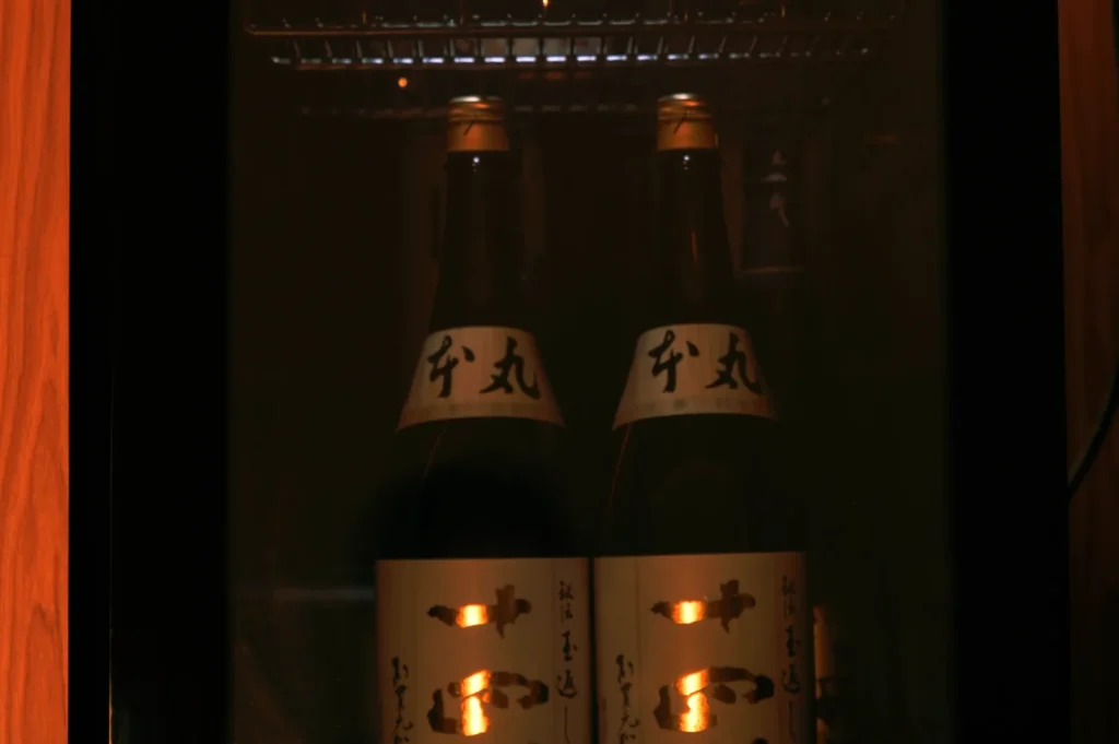 Bottles of sake stored in a refrigerator, illuminated from within.