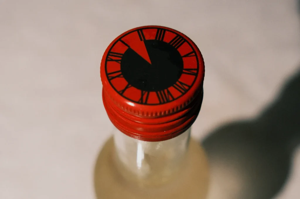 A close-up of a bottle cap featuring a design resembling a clock face with red accents.