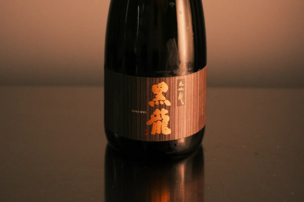 A bottle of sake with a dark label featuring Japanese characters.