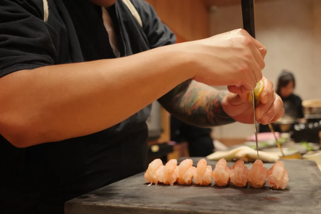A person preparing sushi with a focus on their hands and the sushi on a wooden board.