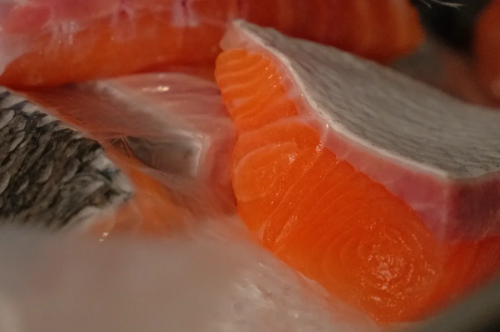 Close-up of various cuts of salmon, showing the distinct orange flesh and fatty layers.