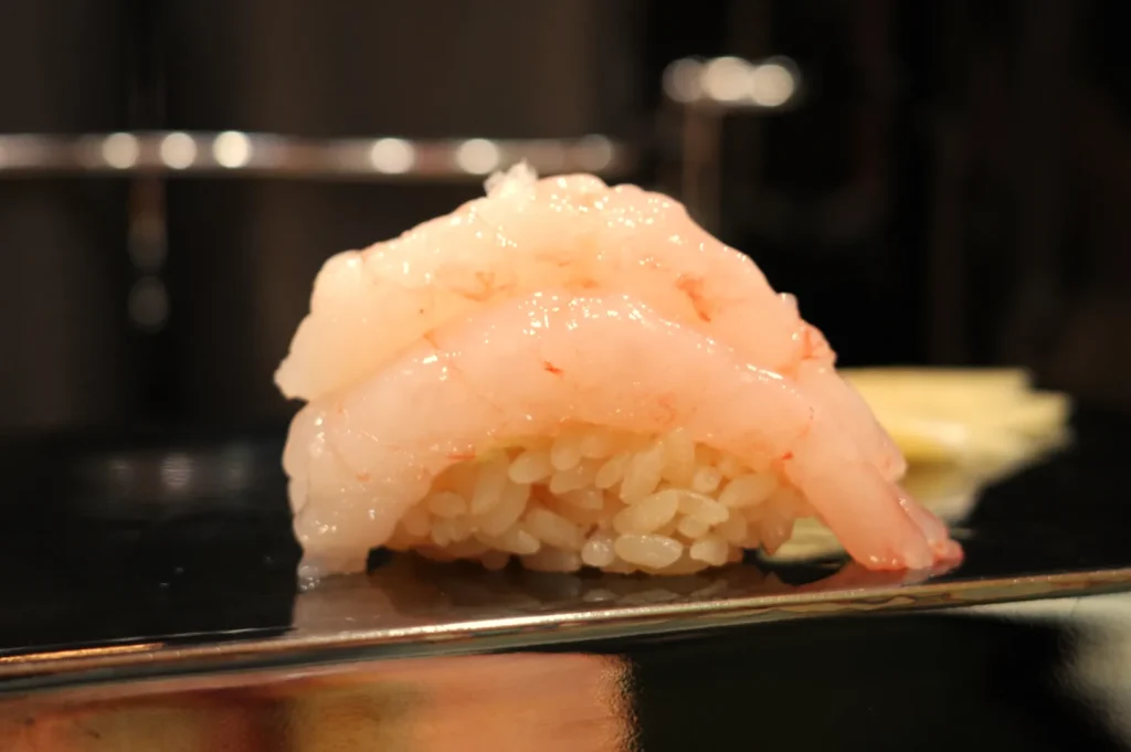 A piece of sushi featuring a mound of shrimp on a small bed of rice.